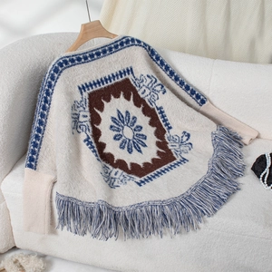 Close-up of vintage knit poncho featuring ethnic geometric patterns and long fringe trim
