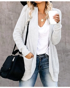 Detail of light grey chunky knit cardigan featuring large pockets and open front design