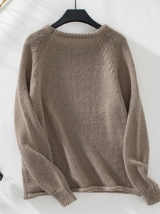Detail of a brown knit sweater showing the classic crew neck and fine raglan sleeve texture