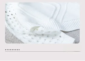 Détail de l'ourlet du pull en maille ajourée blanche avec bords côtelés et motifs fins
