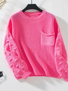 Detail of hot pink knit sweater featuring 3D pom-pom sleeves and front pocket texture