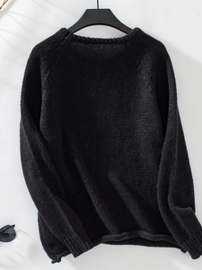 Detail of black knit sweater featuring chunky texture and round neckline for winter