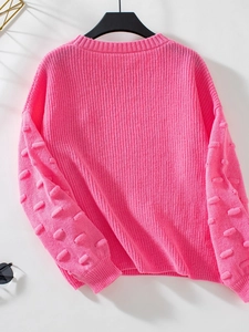 Detail of pink knitted sweater showing textured rib knit and 3D puff ball sleeves