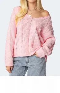 Detailed close-up of cable knit texture and V-neckline on a pink oversized sweater