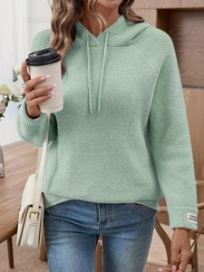 Dettaglio felpa con cappuccio in maglia verde menta con etichetta e tessuto morbido