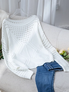 Détail du pull en maille ajourée blanche montrant des motifs de losanges et texture