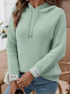 Dettaglio di felpa con cappuccio in maglia verde chiaro con coulisse e texture