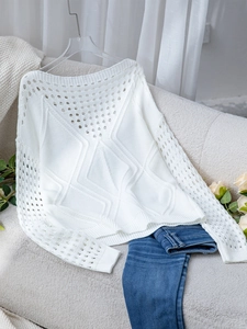 Détail d'un pull en maille ajourée blanche montrant des motifs au crochet géométriques