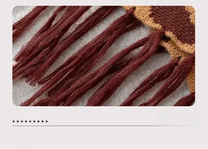 Macro shot of geometric jacquard knit hem with deep red tassels for winter poncho shawl
