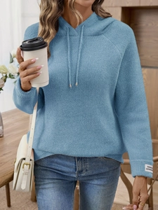 Dettaglio del maglione blu con cappuccio, tessuto testurizzato ed etichetta sulla manica