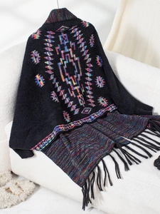 Detail of Aztec geometric knit cardigan with ethnic patterns and fringe hem on sofa