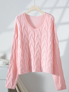 Detail of pink cable knit sweater showing V-neckline and textured chunky stitch