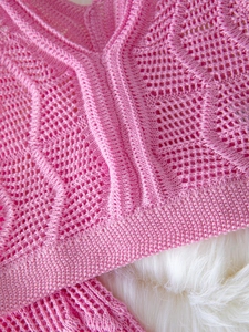 Macro detail of pink hollow knit fabric with geometric patterns and texture