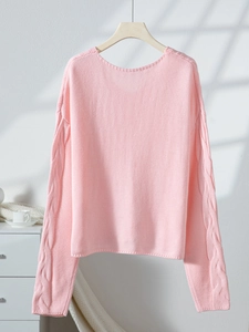 Detail shot of the pink V-neck sweater featuring intricate cable knit textures on sleeves