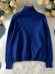 Elegant navy blue long sleeve knit sweater with a turtleneck on white plush rug