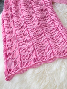 Pink wave texture knit crop top and skirt set displayed on soft white faux fur background