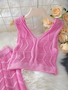 Detail of pink crochet knit set with hollow wavy pattern and V-neck top on a hanger