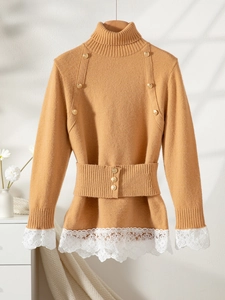 Detail of camel knit sweater featuring gold buttons and white lace trim on the hem