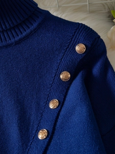 Close-up of royal blue knit sweater featuring elegant gold buttons with crest engraving