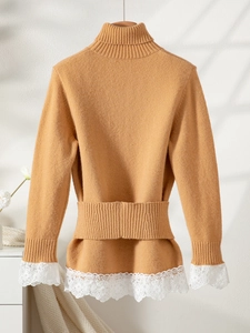 Detail of elegant knit sweater showing waist ribbing and intricate white lace trim on hem