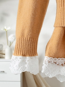 Close-up of ribbed cuffs with delicate white lace crochet on a mustard yellow knit top