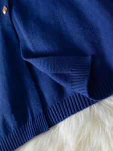Detailed close-up of dark blue knit fabric with an elegant gold embossed button decoration