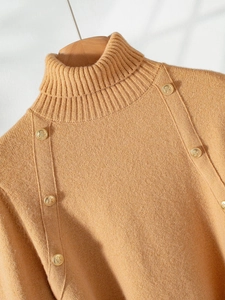 Detail of camel high-neck knit sweater featuring decorative gold-tone shoulder buttons