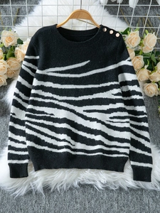 Close-up of zebra pattern knit sweater with decorative gold buttons on the shoulder