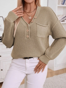 Detail of waffle knit texture and wooden buttons on a beige V-neck sweater cardigan