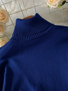 Close-up of navy blue knit sweater featuring a ribbed turtleneck and premium fabric texture