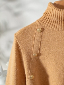 Detail of elegant camel knit sweater showing golden embossed buttons on the collar