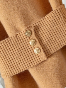 Detail of camel knit sweater featuring ribbed cuffs and vintage gold heraldic buttons
