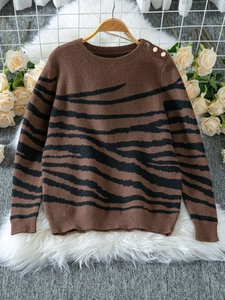 Detail of shoulder gold buttons and zebra print texture on brown knit sweater