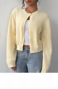 Close-up of pale yellow knit cardigan with round neck and matching tonal buttons