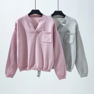 Close-up of V-neck knitted sweaters in pink and grey showing ribbed cuffs and chest pocket