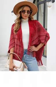Détail d'un poncho en tricot rouge à rayures avec des finitions à franges denses