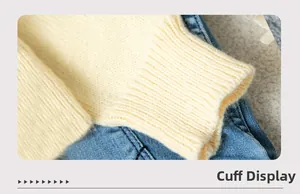 Detail of ribbed cuff on a cream knit cardigan with blue denim fabric background