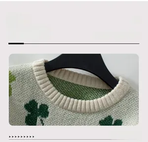 Détail du col rond côtelé et du motif jacquard tricoté de trèfle vert sur le pull