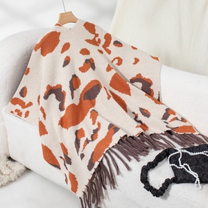 Close-up of contrast leopard print knit shawl featuring long tassels and soft texture