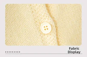 Close-up of cream knit fabric texture with matching round button on the cardigan