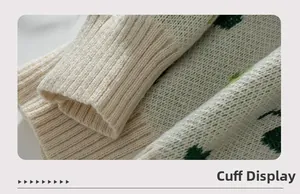 Détail du poignet côtelé du pull en tricot jacquard trèfle crème et vert foncé