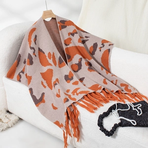 Detail of knit leopard print shawl with long orange tassels and soft knit texture