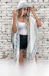 Detail of bohemian white knit poncho with colorful geometric patterns and long tassels
