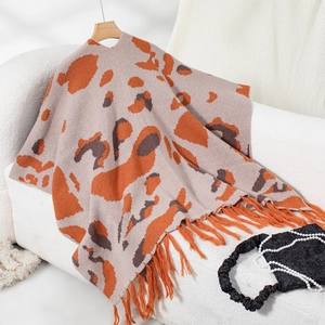 Macro detail of knit poncho featuring leopard print texture and soft fringe hem tassels