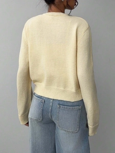 Back view of woman wearing cream crewneck knit sweater with light blue denim jeans