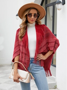 Détail d'un poncho tricoté rouge et blanc avec de longues franges sur l'ourlet pour l'automne