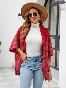 Détail d'un poncho en maille à rayures rouges avec franges denses et texture douce