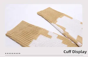 Détail des poignets de pull en maille avec motif jacquard géométrique jaune et blanc