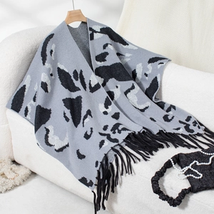 Detailed view of leopard print knit poncho with black fringe trim on a soft base