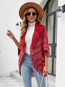 Détail d'un châle en tricot rouge avec franges et rayures sombres pour une tenue d'automne